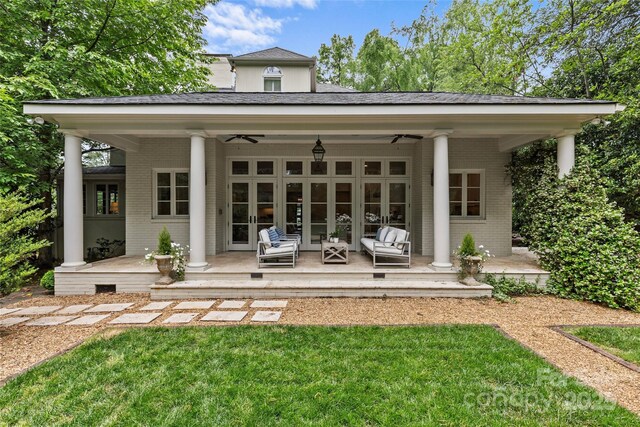 back of property with brick siding, a ceiling fan, and a yard