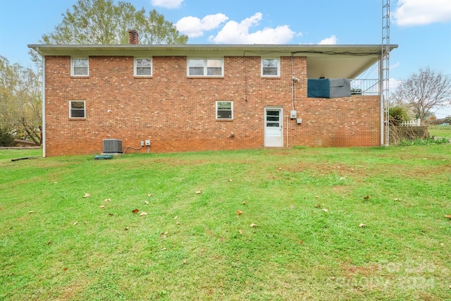 rear view of house featuring a lawn and central AC