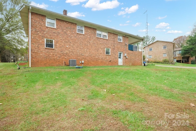 rear view of house featuring central AC unit and a yard