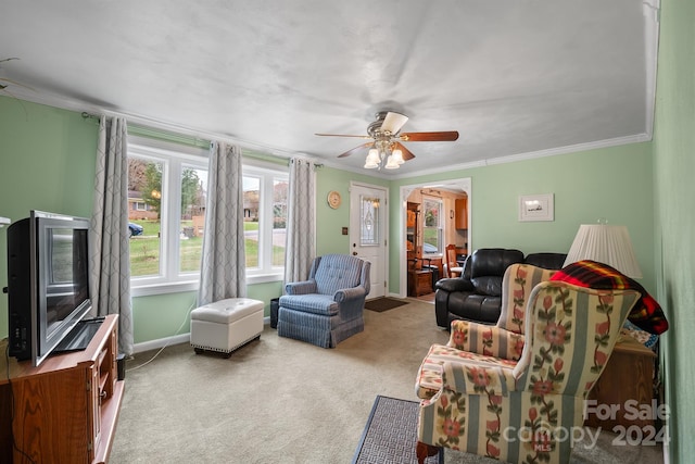 carpeted living room with ceiling fan and ornamental molding