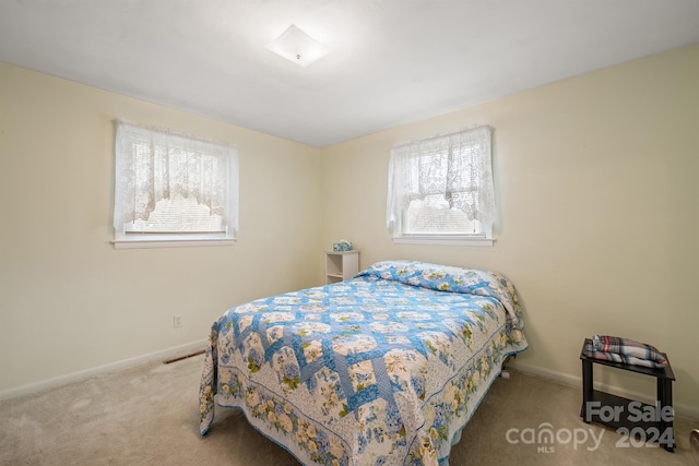 bedroom featuring light carpet and multiple windows