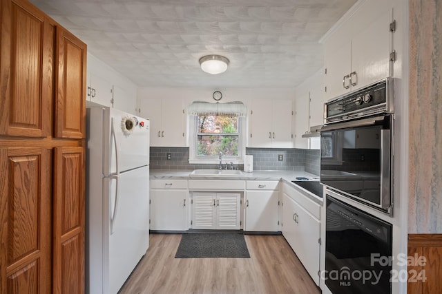 kitchen featuring white refrigerator, white cabinetry, oven, and sink