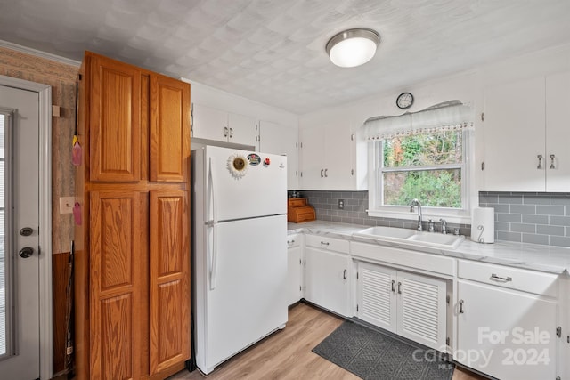 kitchen with decorative backsplash, sink, white refrigerator, light hardwood / wood-style floors, and white cabinetry