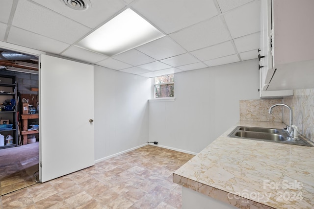 basement featuring a paneled ceiling and sink