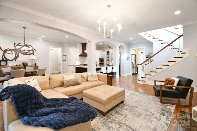 living room with a notable chandelier, wood-type flooring, and ornamental molding