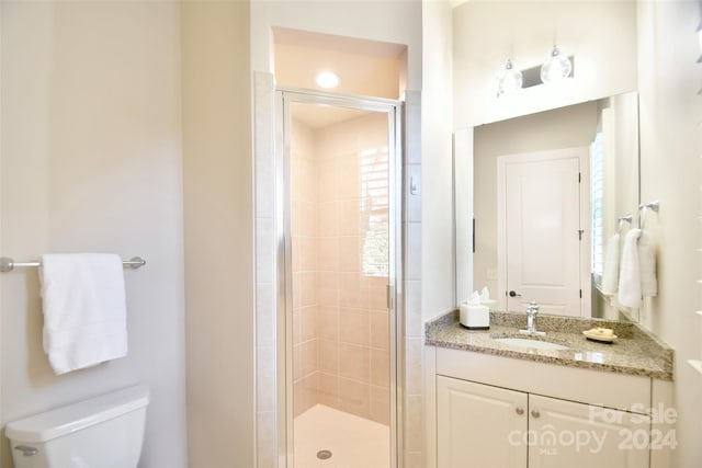 bathroom featuring toilet, an enclosed shower, and vanity