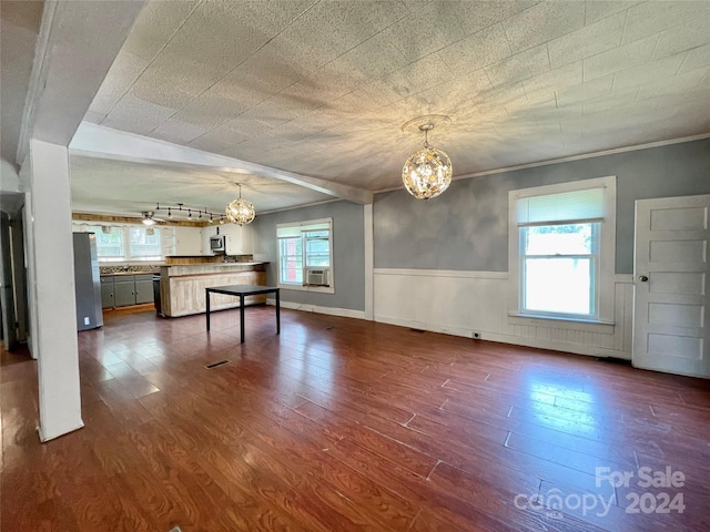 interior space with ornamental molding, dark wood-type flooring, an inviting chandelier, and a healthy amount of sunlight