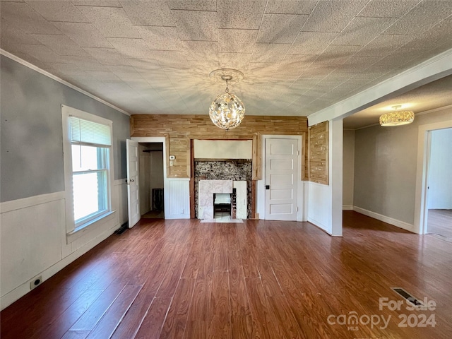 unfurnished living room with hardwood / wood-style flooring, a high end fireplace, ornamental molding, and wooden walls