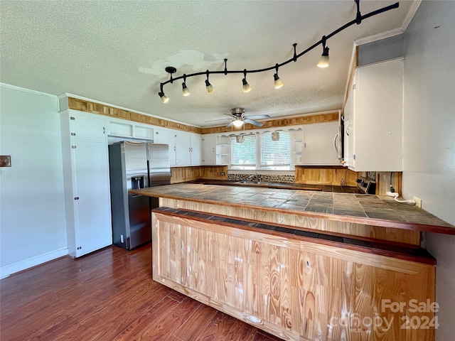 kitchen with crown molding, stainless steel refrigerator with ice dispenser, dark hardwood / wood-style floors, a textured ceiling, and tile counters