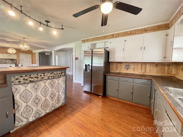 kitchen with gray cabinetry, white cabinetry, light hardwood / wood-style flooring, stainless steel fridge, and a textured ceiling