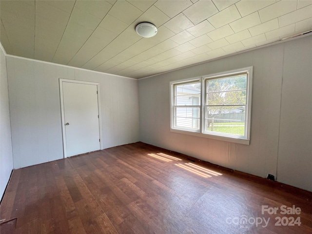 empty room featuring dark wood-type flooring and ornamental molding