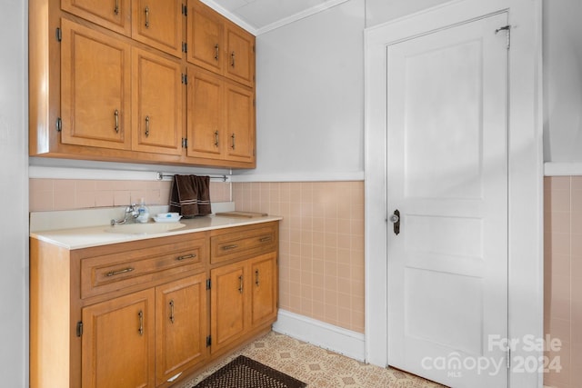 kitchen featuring ornamental molding, light tile patterned floors, sink, and tile walls