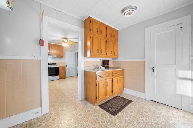 kitchen featuring range, tile walls, ornamental molding, and ceiling fan