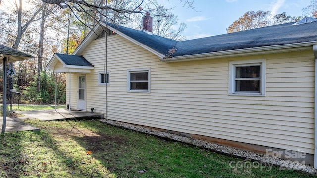 view of side of home featuring a lawn and a patio