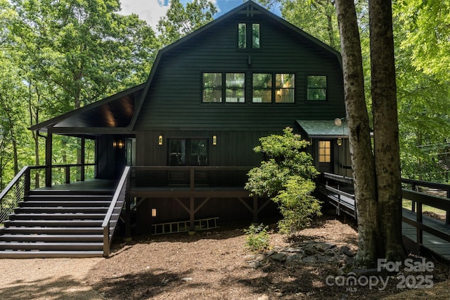 back of property with stairs, a gambrel roof, and a shingled roof