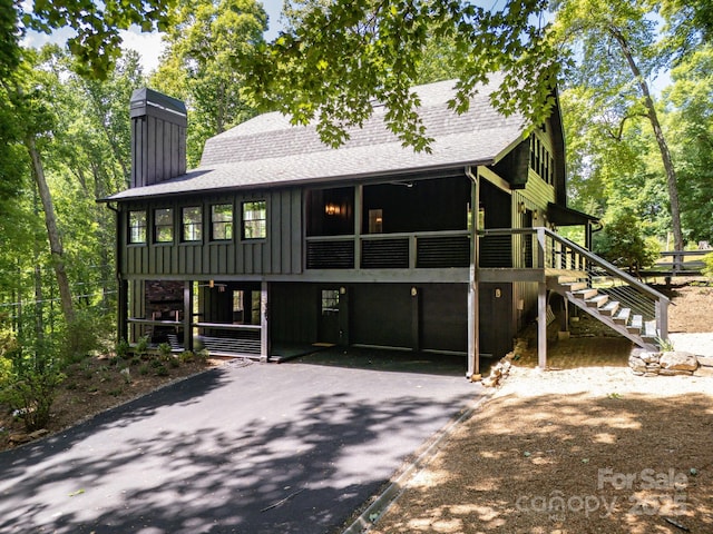 view of front of home with stairs, board and batten siding, and roof with shingles