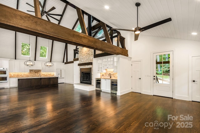 unfurnished living room with beverage cooler, dark wood-type flooring, and ceiling fan