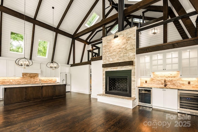 unfurnished living room with a sink, wine cooler, an inviting chandelier, and dark wood-style flooring