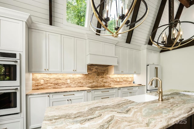 kitchen featuring tasteful backsplash, black electric stovetop, double oven, high end refrigerator, and a sink