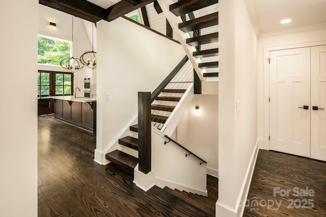 stairway with baseboards, a towering ceiling, and wood finished floors