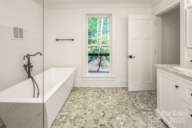 full bathroom featuring vanity, baseboards, visible vents, a freestanding tub, and crown molding