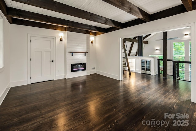 unfurnished living room with baseboards, wood finished floors, beverage cooler, and a fireplace