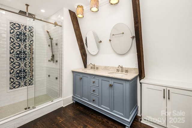 full bath with a shower stall, wood finished floors, double vanity, and a sink