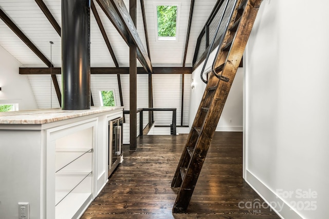 stairs featuring baseboards, beamed ceiling, a skylight, wood finished floors, and plenty of natural light