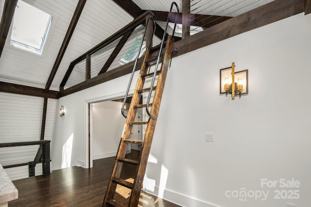 stairs with baseboards, vaulted ceiling with skylight, and wood finished floors