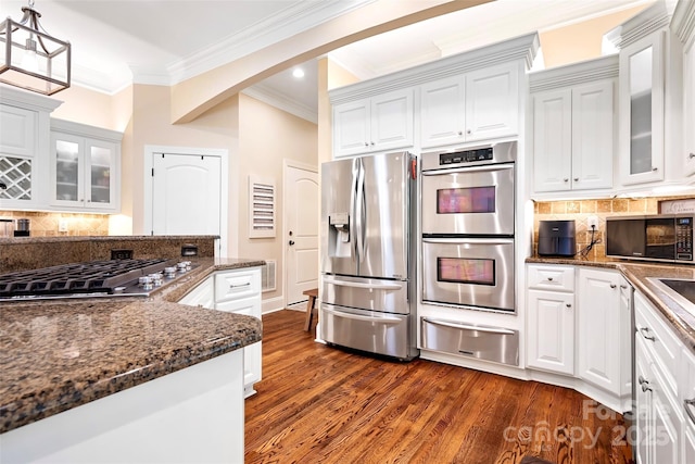 kitchen featuring stainless steel appliances, white cabinetry, pendant lighting, and dark hardwood / wood-style flooring