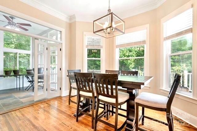 dining area with crown molding, ceiling fan with notable chandelier, and light wood-type flooring