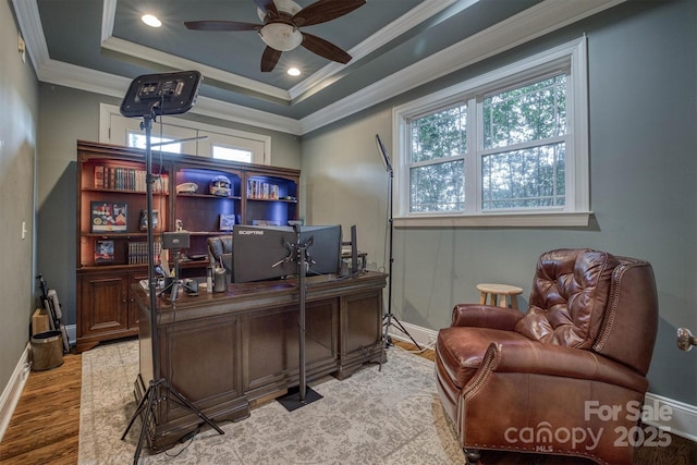 office area featuring wood-type flooring, ornamental molding, ceiling fan, and a tray ceiling