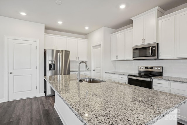 kitchen with white cabinets, appliances with stainless steel finishes, and an island with sink