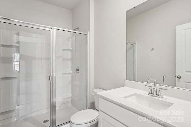 bathroom featuring toilet, a shower with shower door, and vanity