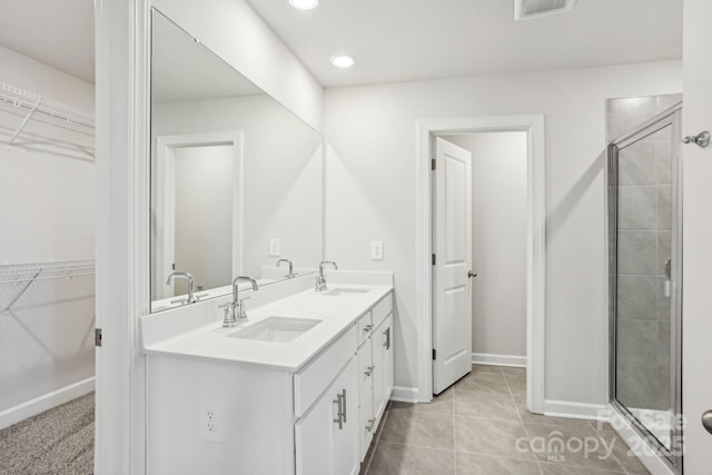 bathroom featuring tile patterned flooring, a shower with shower door, and vanity