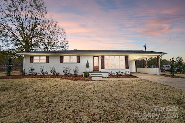 ranch-style house featuring a carport and a lawn