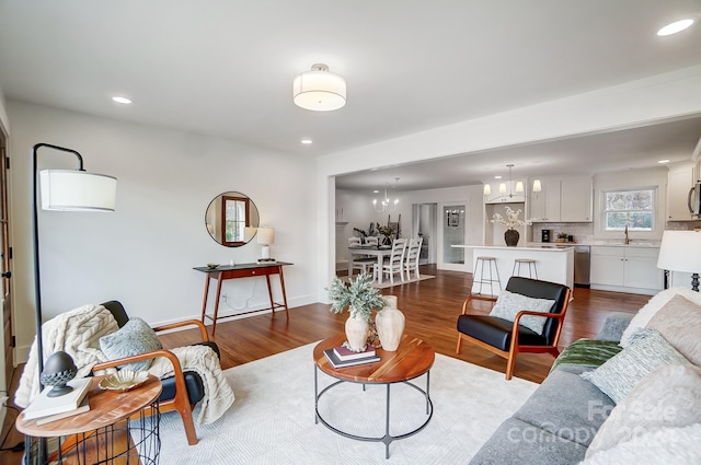 living room with dark hardwood / wood-style flooring, sink, and a chandelier