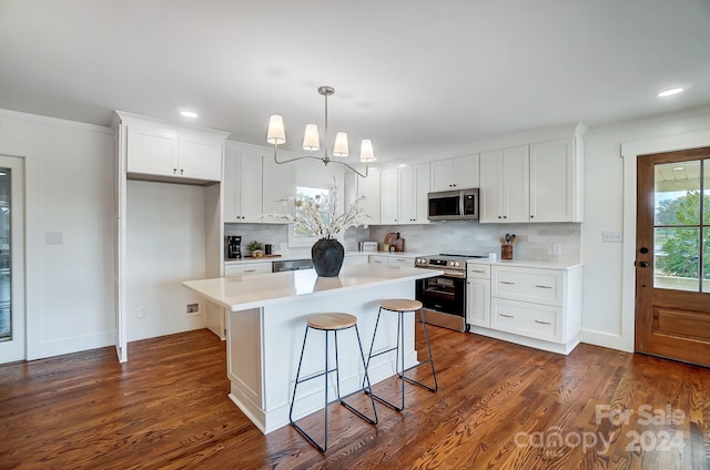 kitchen with appliances with stainless steel finishes, dark hardwood / wood-style flooring, backsplash, a center island, and white cabinetry