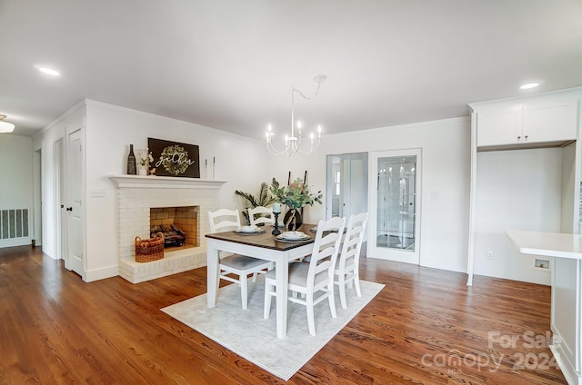 dining space with a fireplace, dark hardwood / wood-style floors, an inviting chandelier, and crown molding