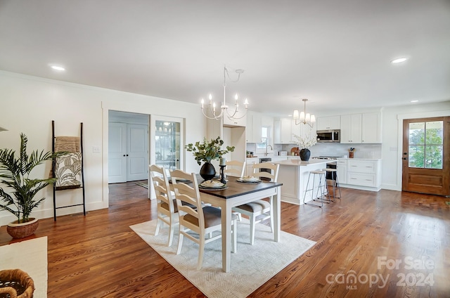 dining room with dark hardwood / wood-style flooring, ornamental molding, sink, and a chandelier