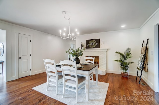 dining area with a fireplace, ornamental molding, dark hardwood / wood-style floors, and a notable chandelier