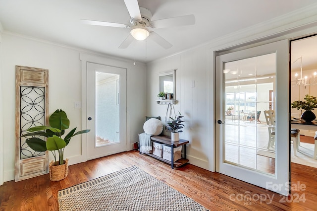 doorway to outside featuring ceiling fan with notable chandelier, a healthy amount of sunlight, wood-type flooring, and crown molding