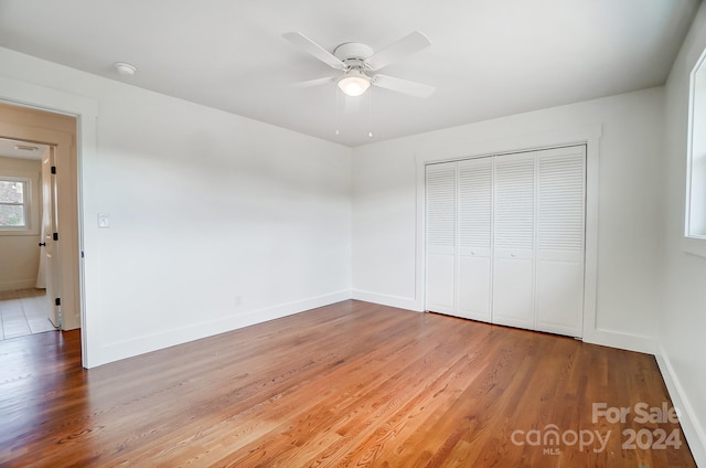 unfurnished bedroom featuring hardwood / wood-style floors, a closet, and ceiling fan