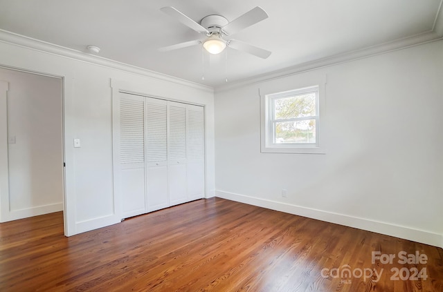 unfurnished bedroom with ceiling fan, dark hardwood / wood-style floors, crown molding, and a closet