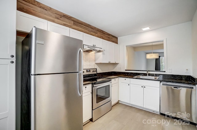 kitchen with appliances with stainless steel finishes, decorative light fixtures, white cabinetry, sink, and light wood-type flooring