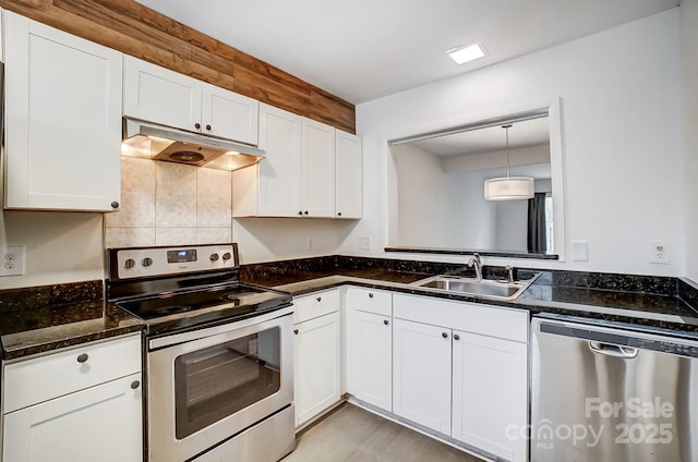 kitchen with sink, dark stone countertops, appliances with stainless steel finishes, pendant lighting, and white cabinets