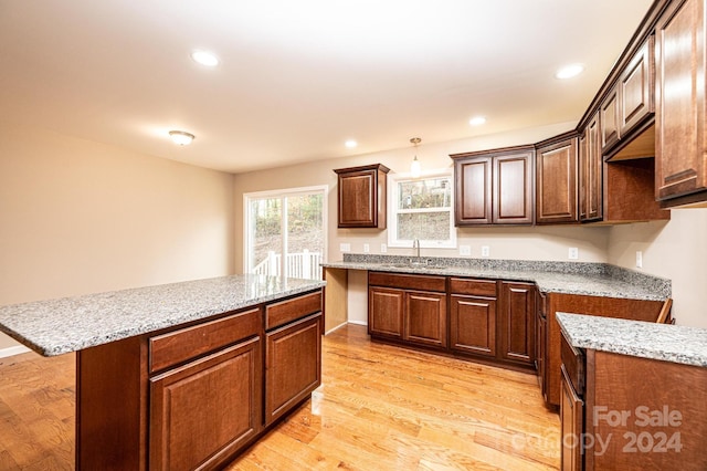 kitchen featuring sink, decorative light fixtures, light hardwood / wood-style floors, a kitchen island, and a breakfast bar area