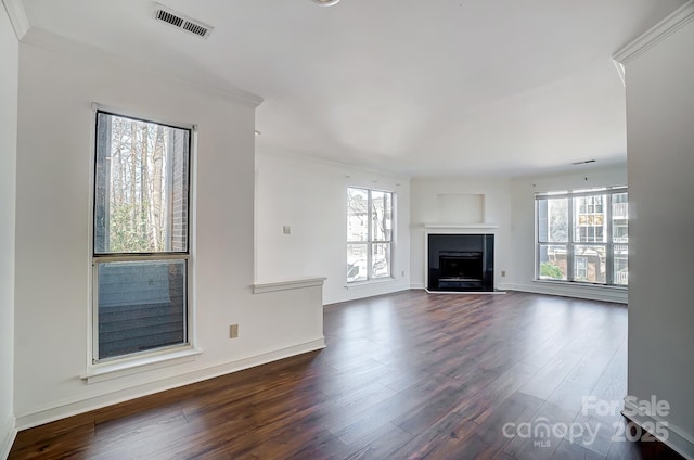 unfurnished living room with dark wood-type flooring, a wealth of natural light, visible vents, and a fireplace with flush hearth