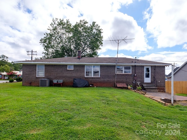 rear view of house featuring a lawn and cooling unit