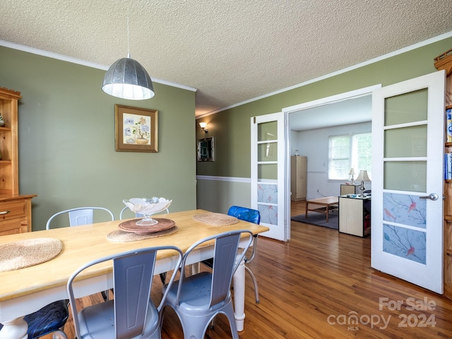 dining space featuring dark hardwood / wood-style flooring, ornamental molding, and a textured ceiling